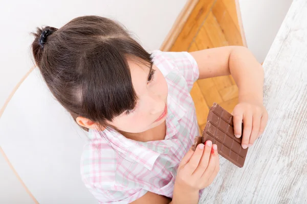 Daughter eating chocolate at home — Stock Photo, Image